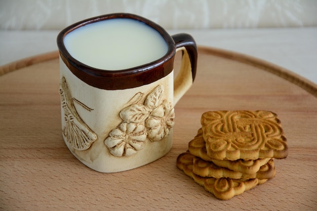 Taza de leche y galletas sobre un fondo de madera Desayuno