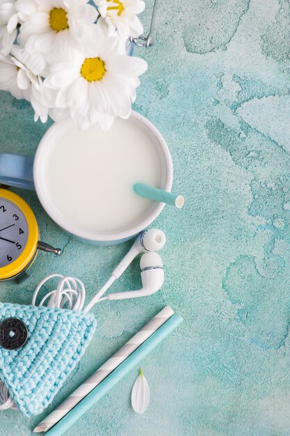 Una taza de leche con pajita, auriculares y soporte