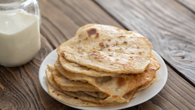 Taza de leche y un plato de tortillas de maíz frito sobre una mesa de madera con textura la vista desde la parte superior