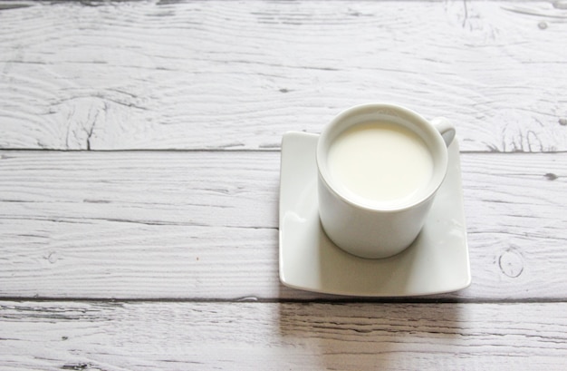 Taza de leche tibia sobre un fondo de madera. Taza blanca con leche. Vista superior. Endecha plana.