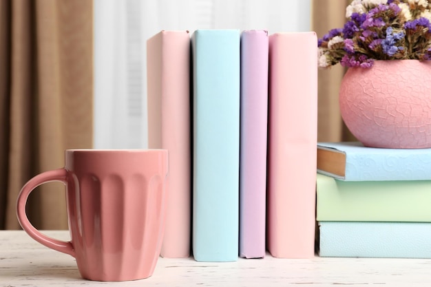 Taza de libros y planta en primer plano de la mesa de madera