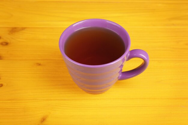 Taza lila con té sobre fondo amarillo