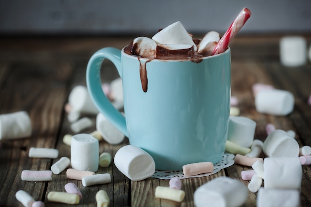 Foto taza llena de chocolate caliente y malvaviscos y dulces.