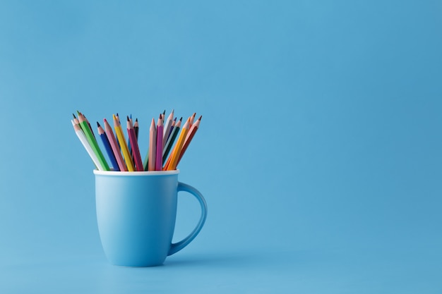 Taza llena de lápices de colores afilados en azul monocromático