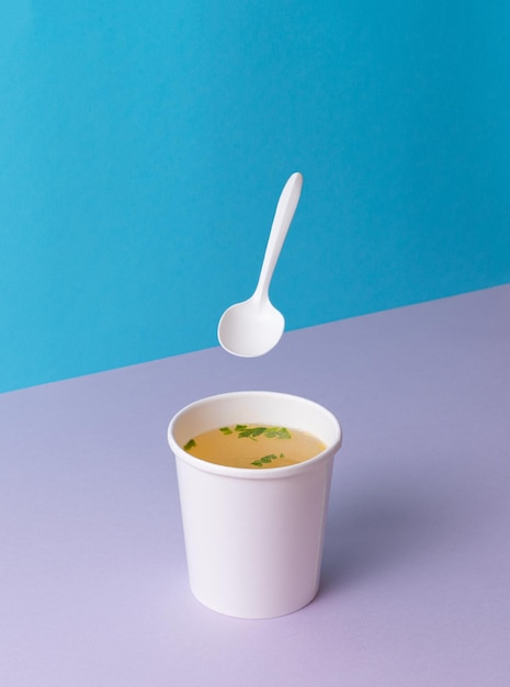 Una taza para llevar con sopa de caldo de pollo