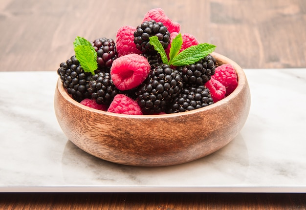 Taza de madera con frutos rojos frescos