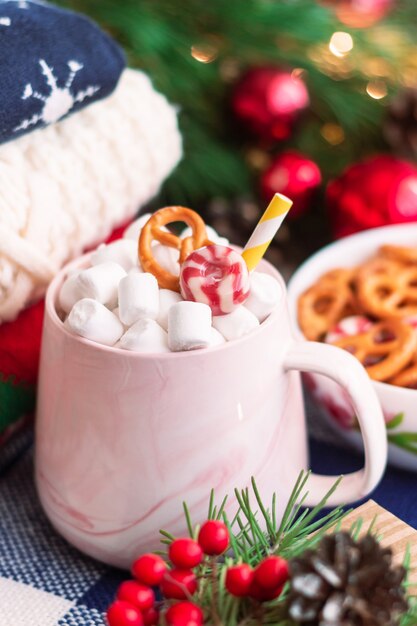 Una taza con malvavisco cerca de suéteres de invierno tazón de pretzels Decoraciones de Navidad y Año Nuevo