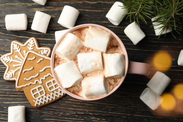 Taza con malvavisco sobre mesa de madera con accesorios navideños