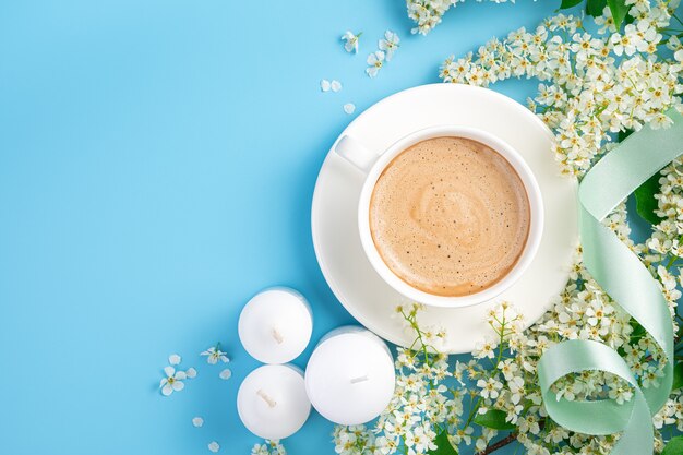 Una taza de la mañana de capuchino flores y velas sobre un fondo azul con espacio para copiar