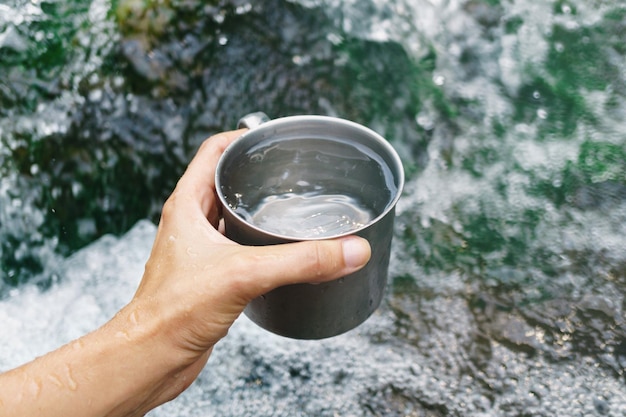 Taza de mano con agua potable de cascada pura