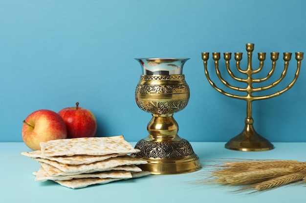 Una taza de manzanas matzah y hanukkiah sobre un fondo azul