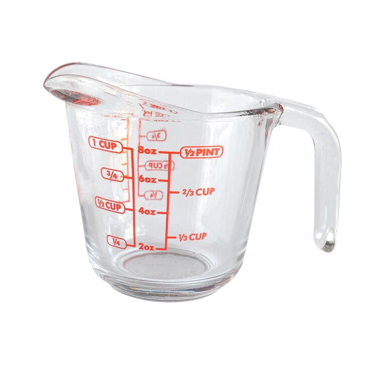 Taza medidora de vidrio sobre fondo blanco.