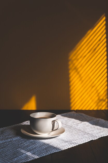 Taza en una mesa de madera en el sol de la mañana