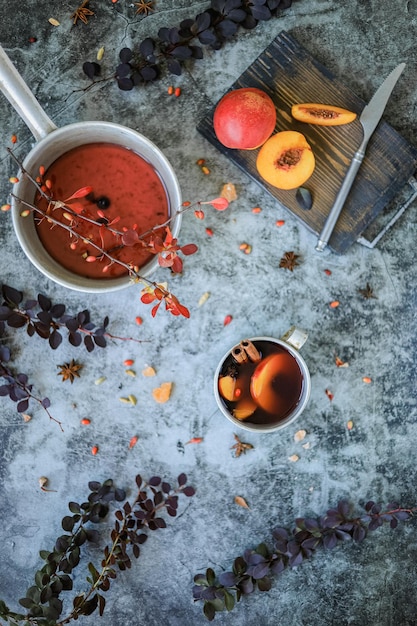Taza de metal con bebida caliente casera sin alcohol de otoño e invierno de bayas y frutas en la mesa
