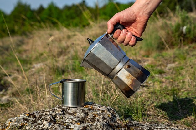 Taza de metal y cafetera en la naturaleza Hacer café Camping en verano