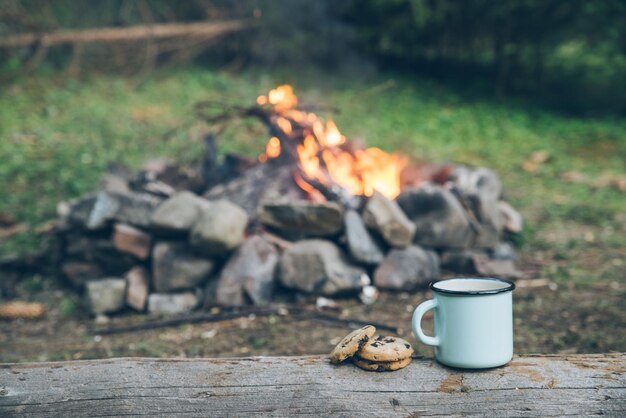 Taza de metal con fuego de té y galletas en el fondo