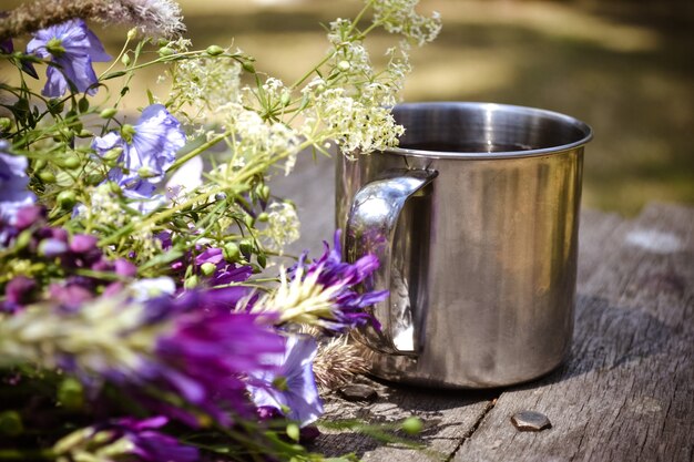 Taza de metal sobre una mesa con filtro de hermosas flores florecientes