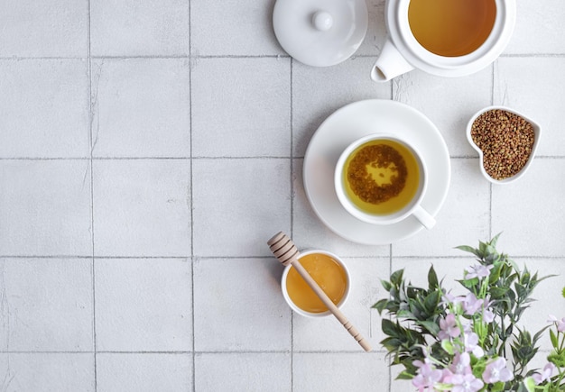 Una taza de miel se sienta en una mesa junto a un ramo de flores.