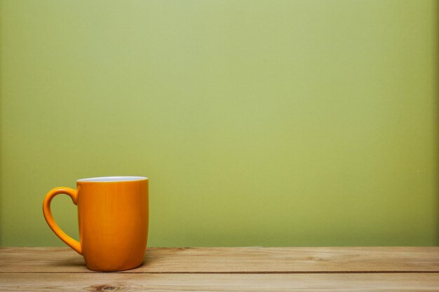 Foto una taza de naranja en la mesa con una pared verde