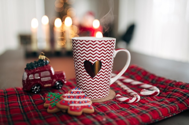 Taza de Navidad blanca roja, galletas, caramelos, piruleta y coche. Foto de alta calidad