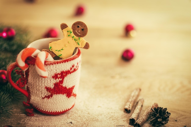 Taza navideña con adornos navideños y galletas