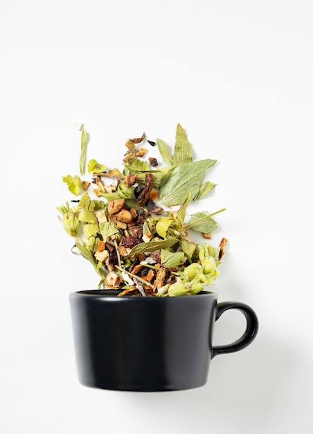 Taza negra de té de hierbas con frutas sobre un fondo blanco. El concepto de bebida saludable. Vista superior y espacio de copia.