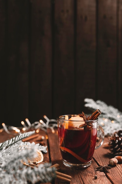 Taza o taza de vidrio con vino caliente en el interior con fondo de mesa de madera