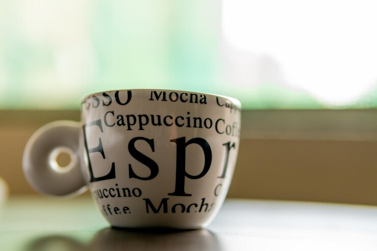Una taza con la palabra café en ella en una mesa con Bokeh
