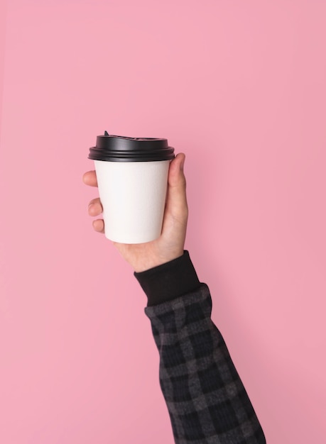 Taza de papel del café del holdinf de la mano. maqueta para el diseño creativo de marca sin fondo rosa.