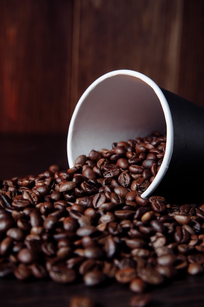 Una taza de papel de café con imagen vertical de granos de café