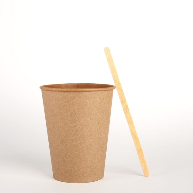 Taza de papel kraft desechable y palo de café de madera sobre fondo blanco Espacio libre para su marca