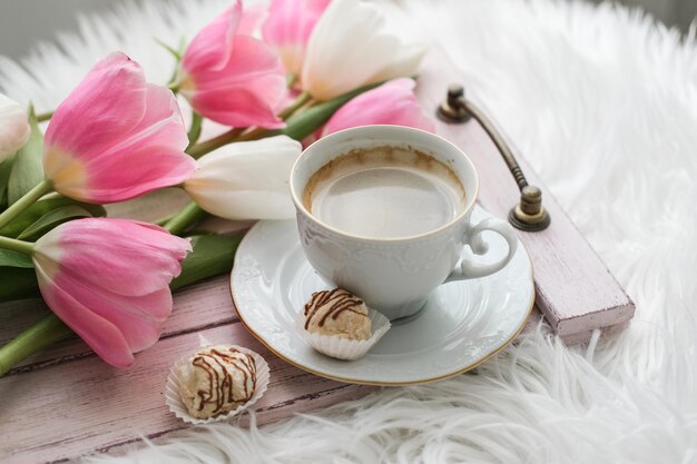 Foto una taza de pastel de café y un ramo de tulipanes en una bandeja de madera