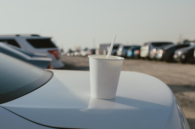 Taza de plástico blanco se encuentra en el maletero del automóvil blanco con fondo de estacionamiento