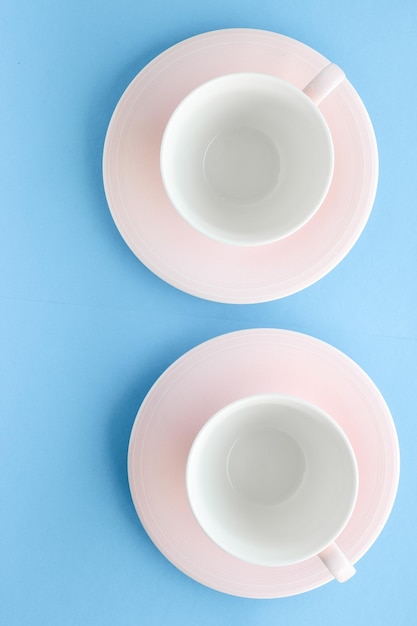 Taza y plato vacíos sobre fondo azul flatlay