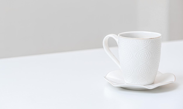 Taza de porcelana blanca sobre una mesa en el interior Platillo blanco y taza de café en la vista lateral de la mesa blanca