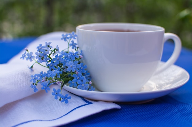 Foto taza de porcelana blanca con té sobre la mesa con mantel azul y servilleta blanca