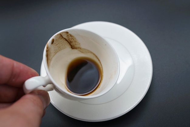 Taza de porcelana de café con leche con restos de posos de café en el fondo