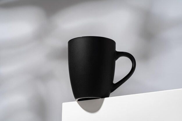 Taza de porcelana negra sobre un fondo gris con sombras