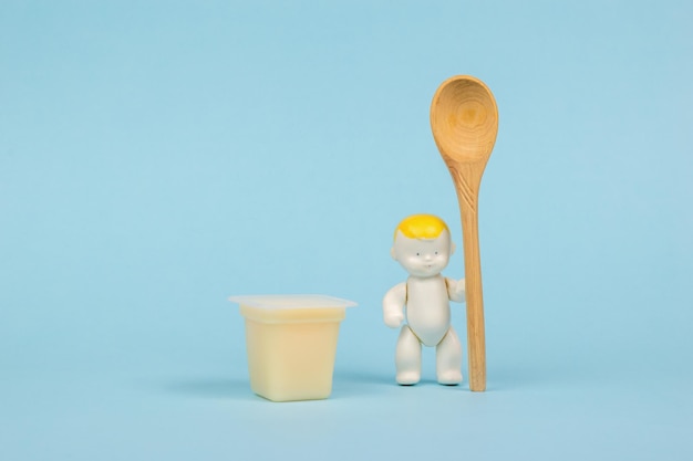 Una taza de postre de plátano y una figurita de bebé con una cuchara. El concepto de comida saludable para bebés.