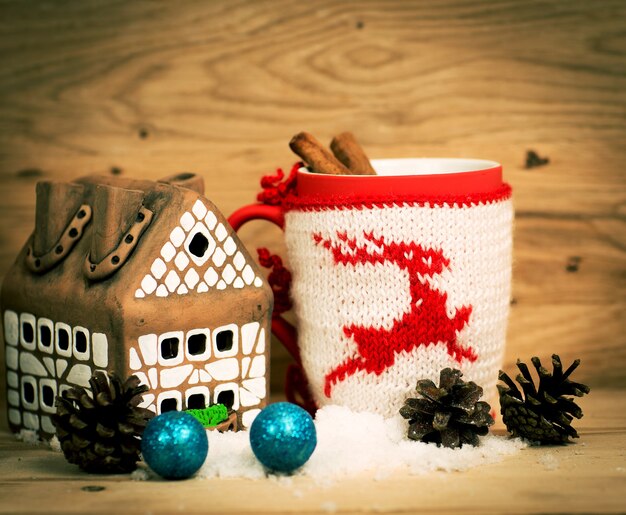 Taza de regalo de té o café con cinta roja y adornos navideños de dulces y especias