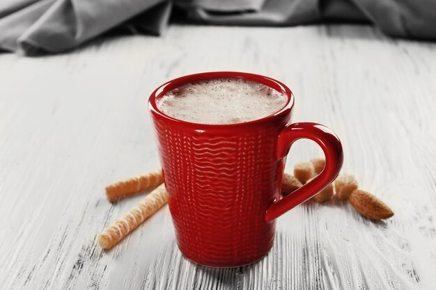 Taza roja de cacao caliente y dulces sobre fondo de madera