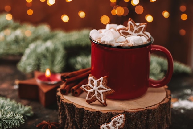 Una taza roja de cacao con malvaviscos y galletas navideñas en un ambiente de año nuevo navideño acogedor