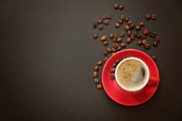 Taza roja de café espresso y granos de café sobre negro