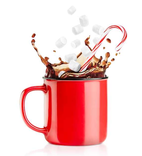 Una taza roja con un chorrito de café y un bastón de caramelo que cae con malvaviscos en un blanco