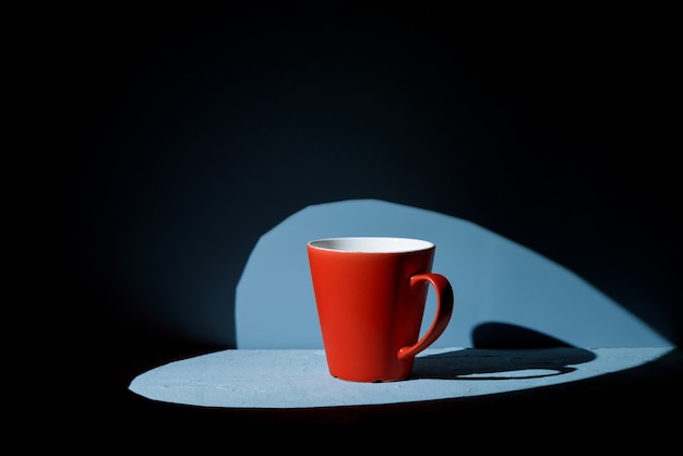 Taza roja sobre superficie azul con foco