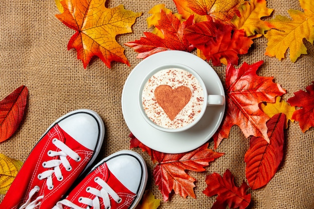 Taza romántica de café y sabuesos con hojas de otoño sobre fondo de arpillera. Vista superior