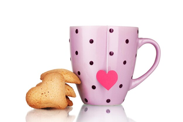 Taza rosa con bolsita de té y galletas en forma de corazón aislado en blanco