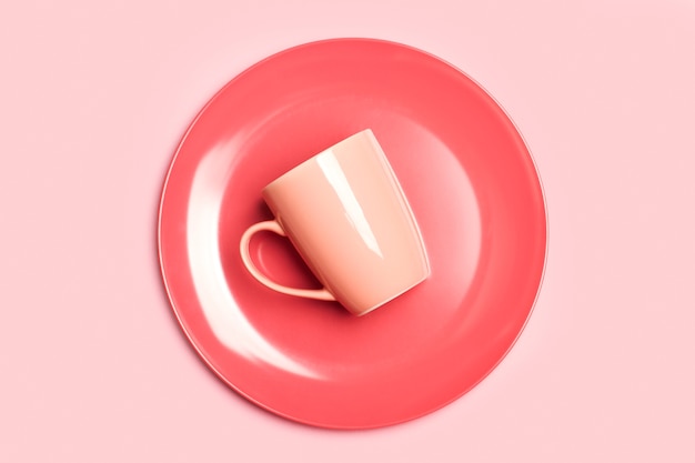 Una taza rosa sobre un plato rosa y sobre un fondo rosa en una vista superior