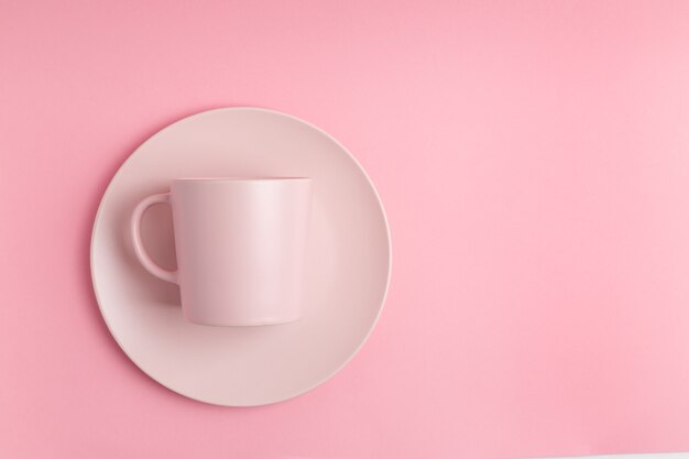 Taza rosa vacía sobre fondo rosa