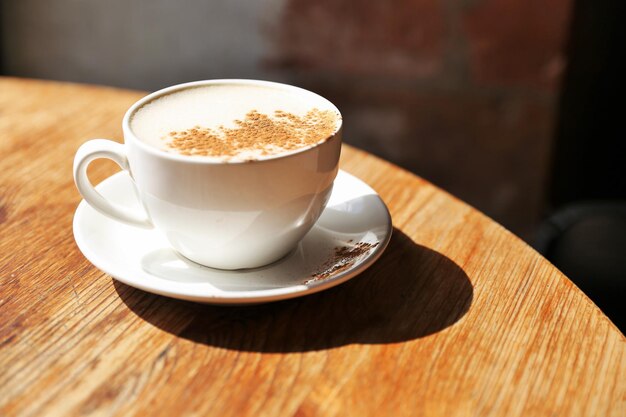 Foto una taza de saboroso latte está de pie en la mesa de madera con textura con el fondo de la pared de ladrillo